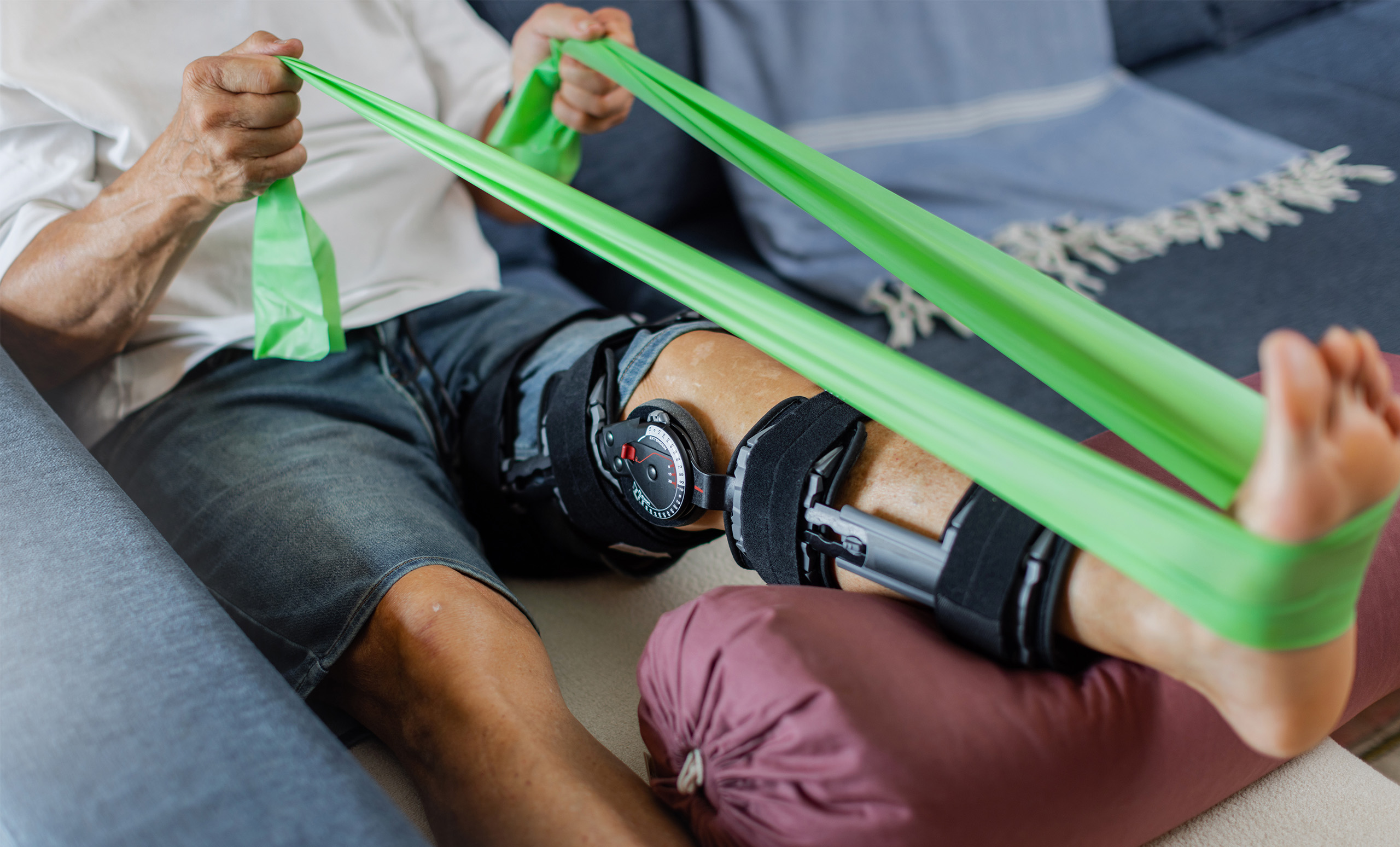 Picture of a man's leg with a knee brace engaging in a physical therapy strength exercise.