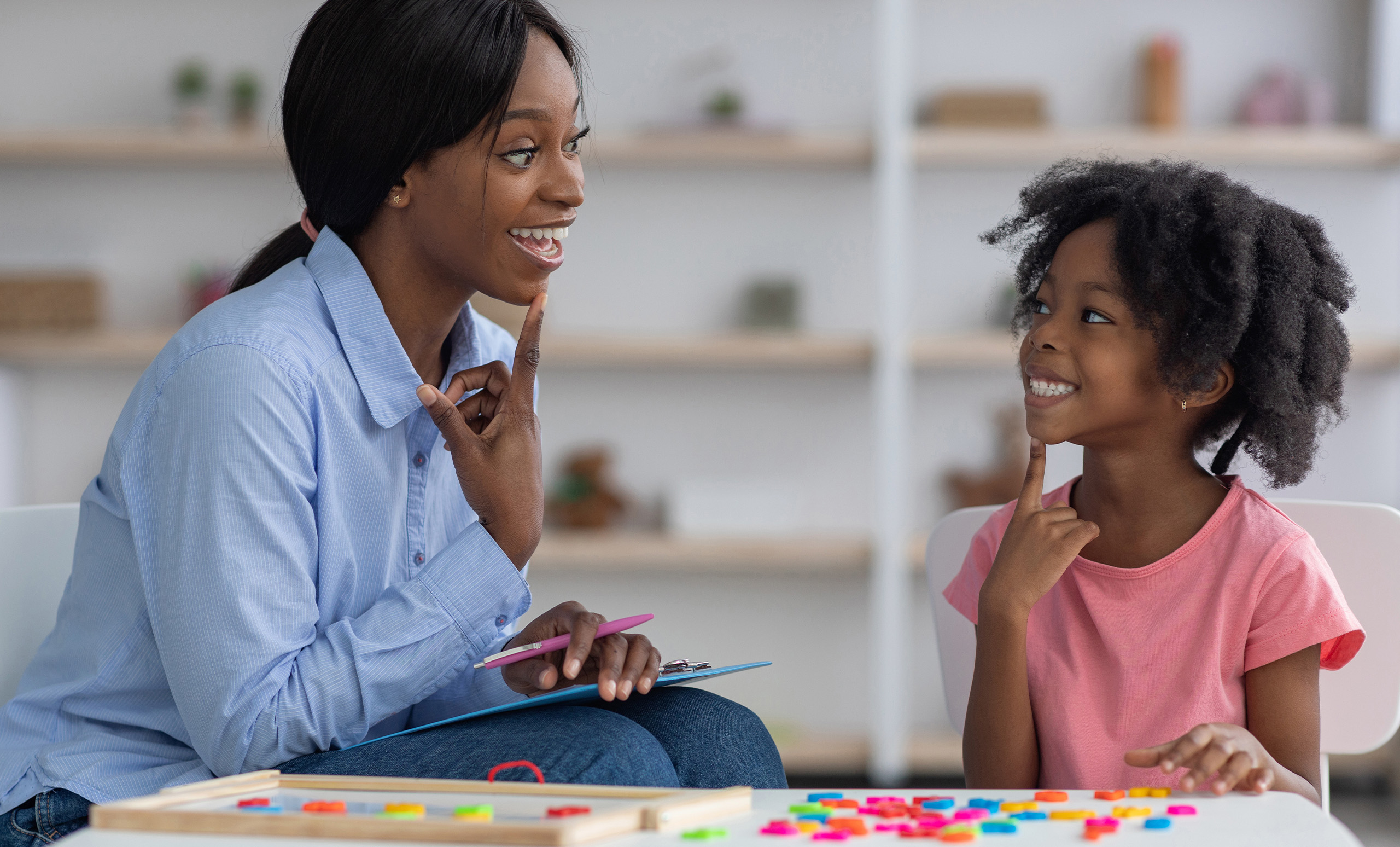 Picture of smiling young girl working with her speech therapist.