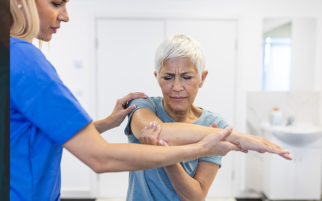 Picture of a woman working with a PT to isolate the source of pain in her shoulder.