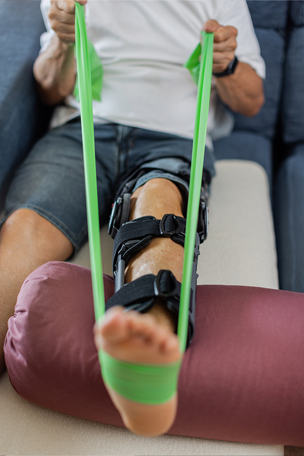 Patient performing knee rehabilitation exercise with resistance band during physical therapy in Chesapeake VA