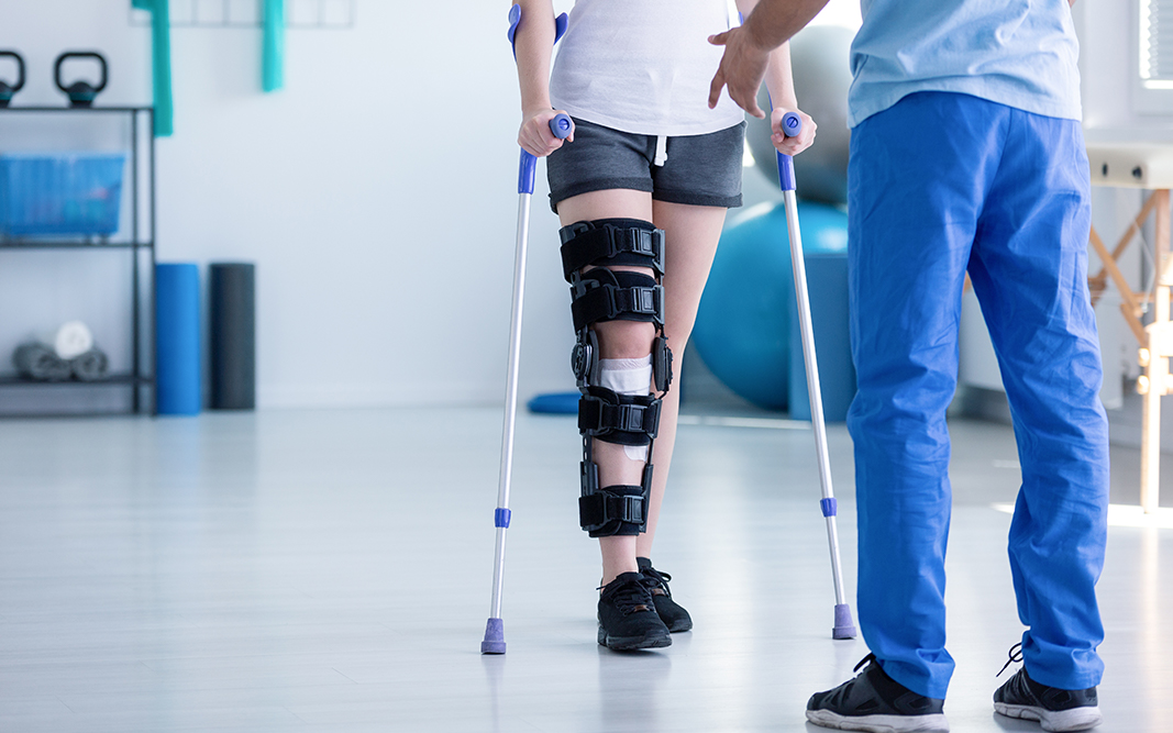 Patient walking with knee brace and crutches during post-surgical physical therapy recovery in Chesapeake VA